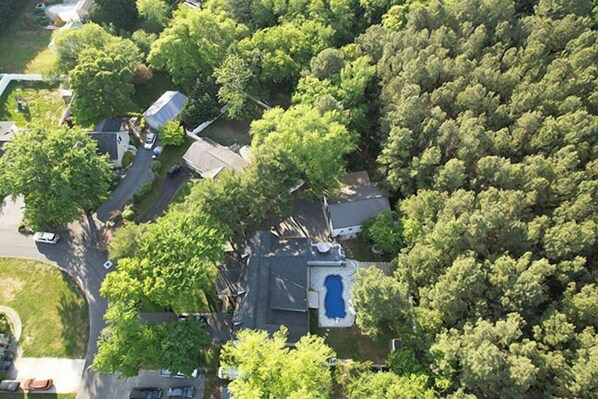 Luchtbeeld van een woongebied met een zwembad, huizen en weelderige begroeiing.
