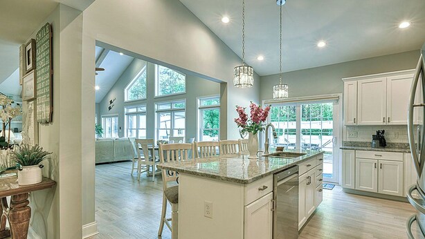 A spacious kitchen with a large island, white cabinetry, and pendant lighting.