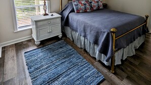 A bedroom with a bed, a nightstand, a lamp, a window with blinds, and a rug. - DAPHNE -  MOBILE BAY CONDO - Great location  (Daphne)