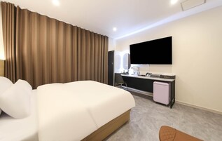 Habitación de hotel con una cama grande, un escritorio, un televisor de pantalla plana, un secador de pelo y un refrigerador pequeño.