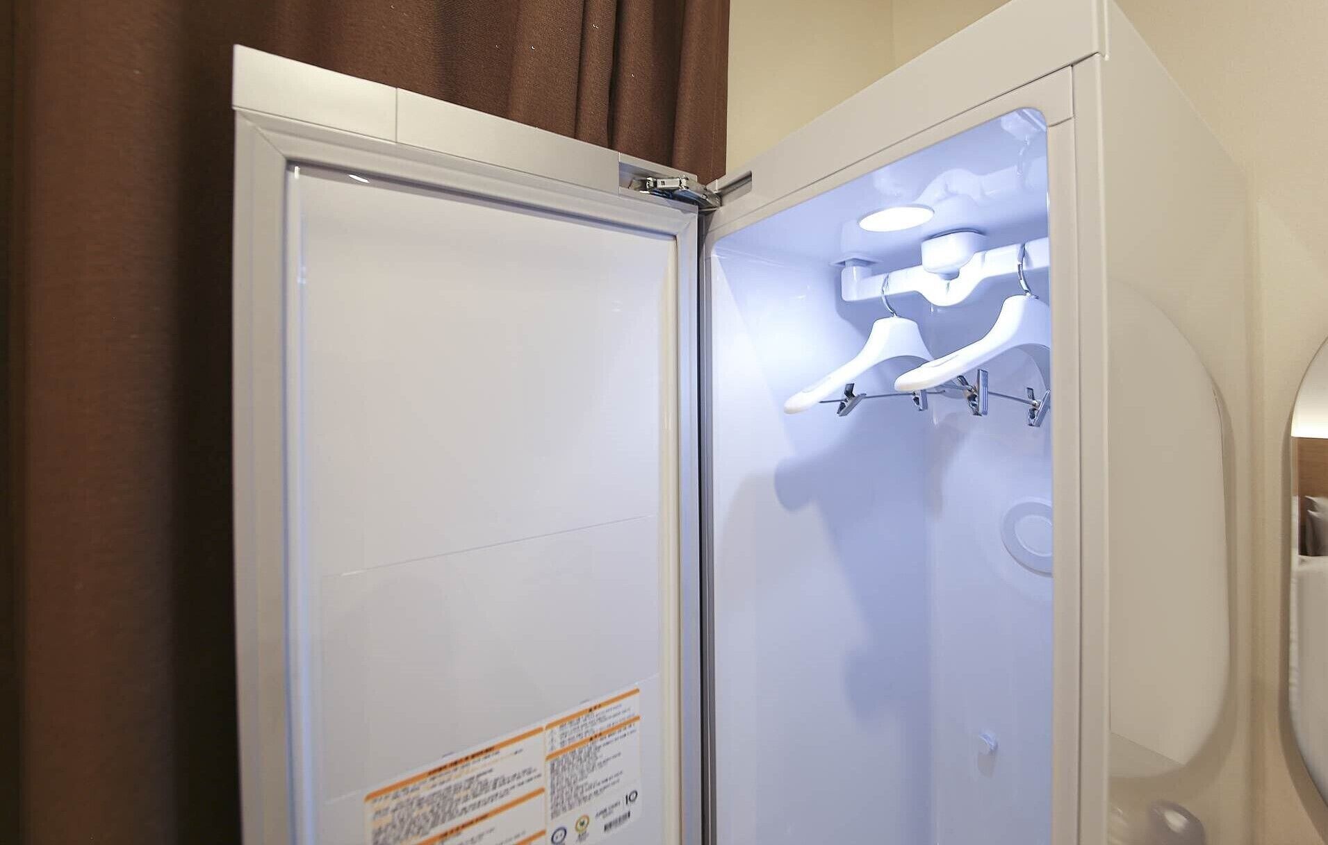 Un baño con una puerta blanca, una cabina de ducha de vidrio y un perchero con toallas blancas.