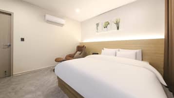 Une chambre d’hôtel dotée d’un grand lit, d’un fauteuil massant, d’un système de climatisation et d’œuvres d’art accrochées au mur.