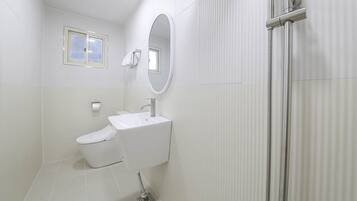Un baño moderno con inodoro, lavamanos y ducha.
