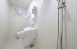 Un baño moderno con inodoro, lavamanos y ducha.