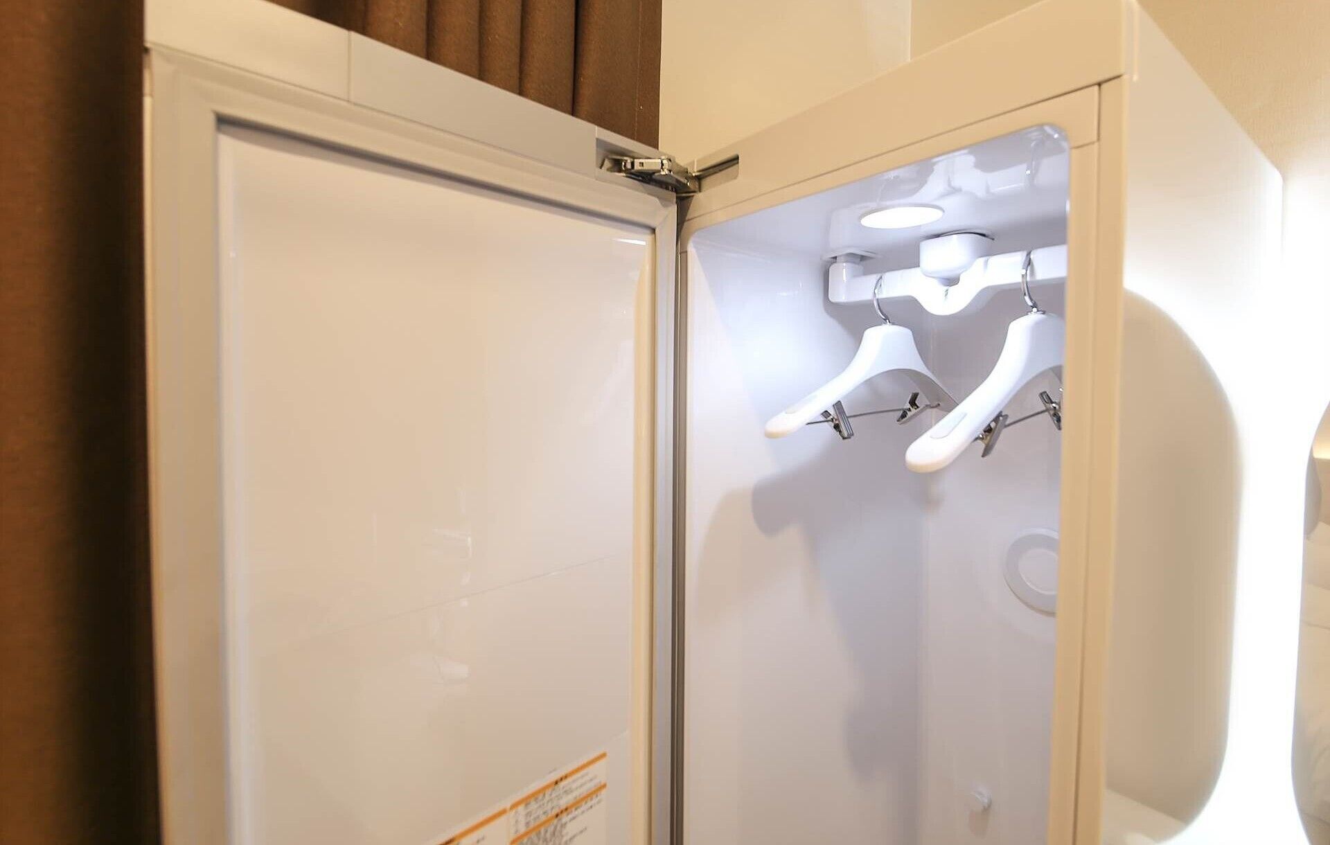 A bathroom with a frosted glass door, white walls, and a towel rack with two white towels.