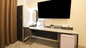 Habitación de hotel con escritorio, televisor de pantalla plana, secador de pelo, teléfono y minibar.