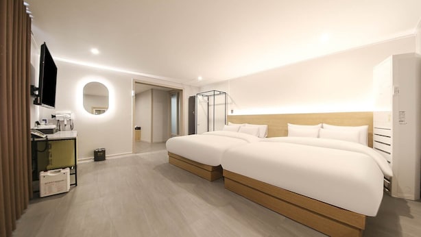 Una habitación de hotel moderna con una cama grande, un televisor, un espejo y un baño visible a través de una puerta abierta.