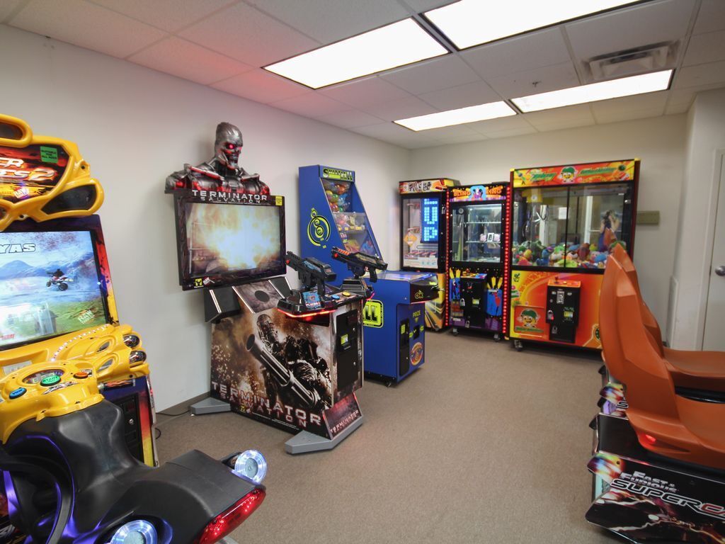 An arcade with various gaming machines, including a Terminator-themed game and a racing game.