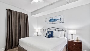 A bedroom with a large bed, two bedside tables, a ceiling fan, and a wall-mounted artwork of a shark. - *Aug 29 - Sept 3 Open! *Beautiful, Gulf Front!* (Panama City Beach)