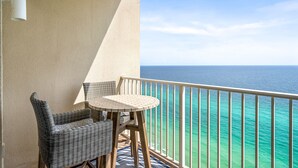 A balcony with a view of the ocean, wicker furniture, and a small round table. - *Aug 29 - Sept 3 Open! *Beautiful, Gulf Front!* (Panama City Beach)