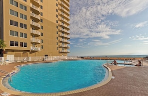Un hôtel doté d’une piscine, offrant une vue sur la plage et comprenant un immeuble à plusieurs étages avec des balcons.
