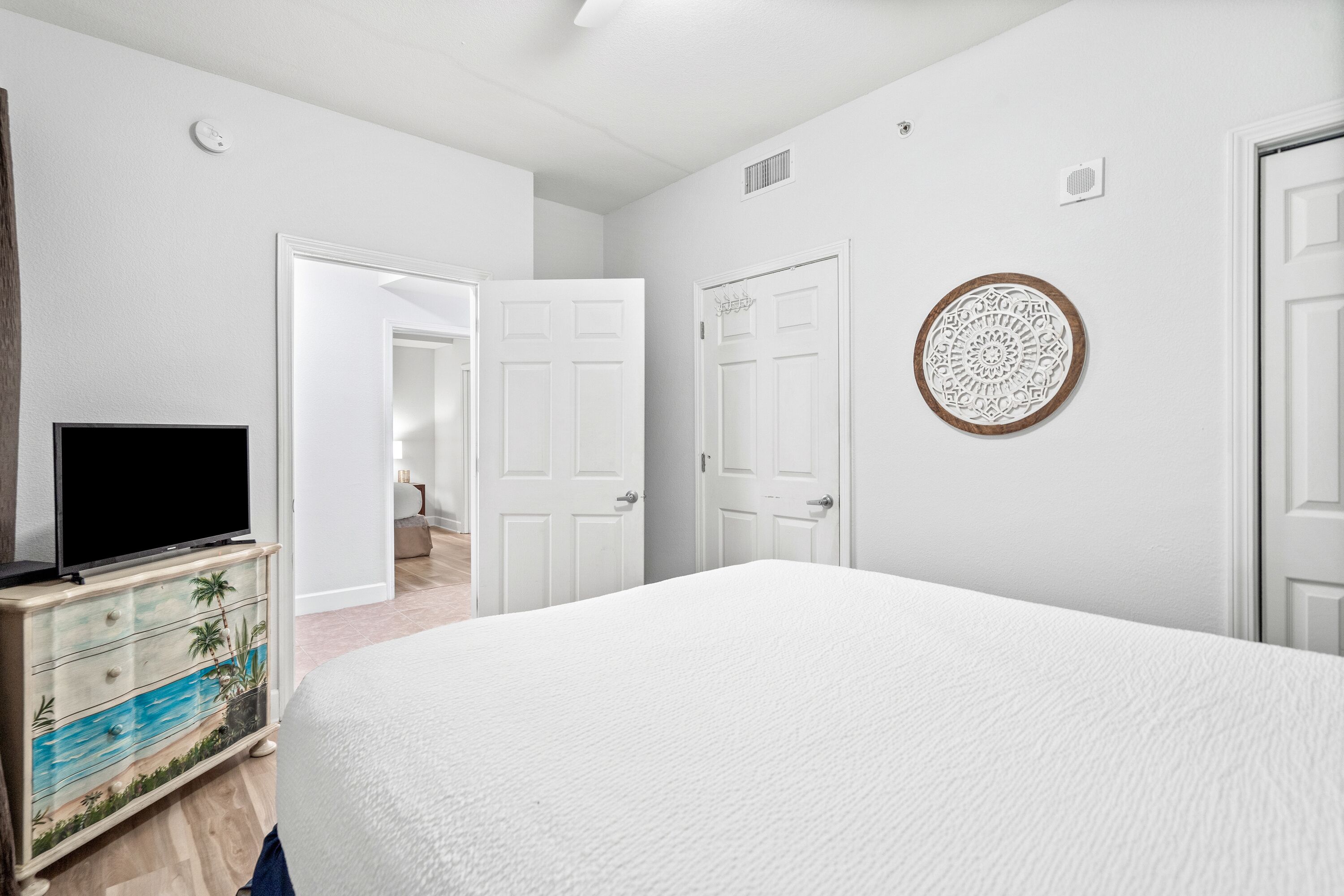 A bedroom with a large bed, a television on a dresser, and white doors.