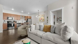 Ein modernes Wohnzimmer mit Sofa, Couchtisch und einer Küche im Hintergrund.