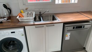 Uma cozinha compacta com máquina de lavar, lava-louças e pia.