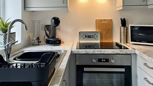 Une cuisine moderne équipée d’un four encastré, d’un four à micro-ondes et d’une plaque de cuisson à induction de la marque Nibblez.