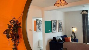 Un coin repas agrémenté d’un grand miroir rond qui reflète le salon.