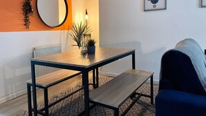 Un salon moderne avec une table à manger en bois, un banc et un fauteuil bleu.