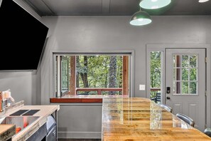 A modern kitchen with a large island, a window with a view of trees, and a door with a window.