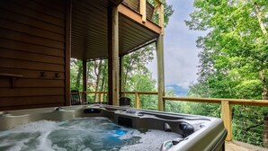 Un jacuzzi en una terraza de madera con vista a abundante follaje.