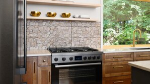Una cocina moderna con estufa a gas Bosch, armarios de madera y salpicadero de piedra.
