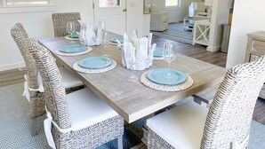 Un coin repas avec une table en bois dressée pour six personnes, entourée de chaises en osier.