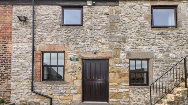 A stone building with a dark brown door, two windows, and a sign reading "Haddon Suite". - Haddon Cottage (Bakewell)