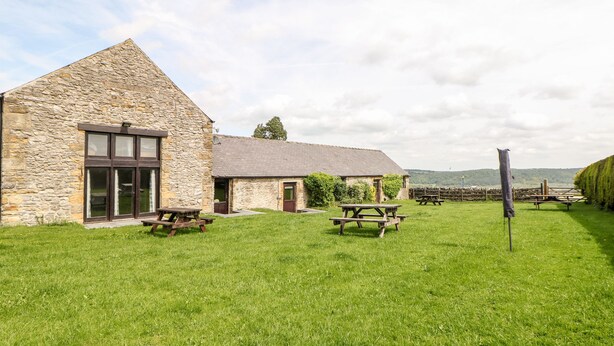A stone building with a large window and a picnic table in the yard. - Monsal Cottage (Bakewell)