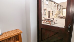A wooden door with a view of a stone building and a picnic table outside. - Monsal Cottage (Bakewell)