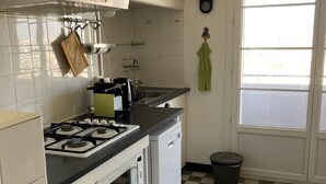 Eine Küche mit weißen Schränken, einem Gasherd, einem Geschirrspüler und einem karierten Boden.