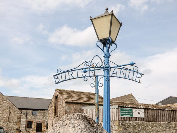 A metal sign with "BURTON MANOR" written on it, mounted on a pole with a lamp on top. - Brendan (Bakewell)