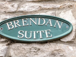 Un letrero de metal verde con la inscripción "BRENDAN SUITE" sobre un muro de piedra.