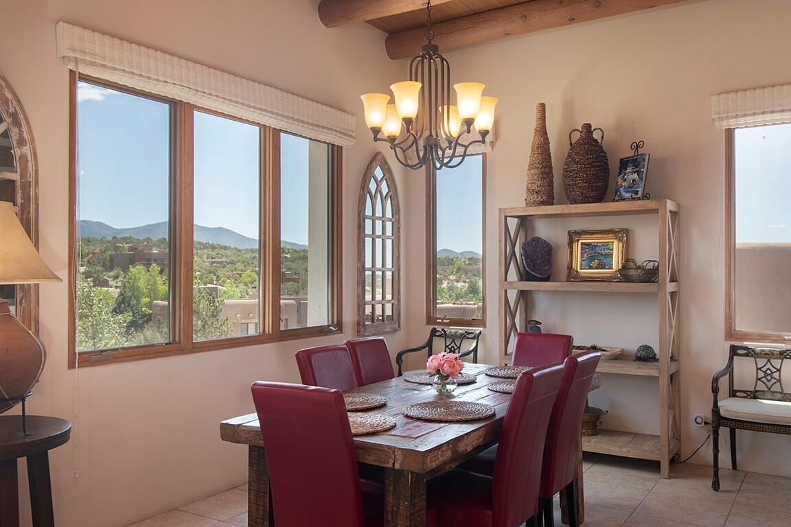 A dining area with a wooden table, red chairs, a chandelier, and a view of the outdoors.
