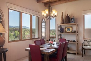 A dining area with a wooden table, red chairs, a chandelier, and a view of the outdoors.