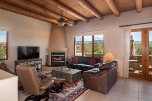 A living room with a fireplace, leather furniture, a television, and a balcony with a view.