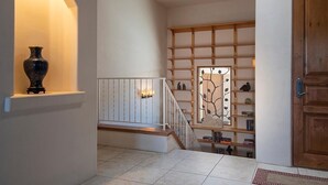 Una escalera con barandilla de madera, un florero sobre una estantería y una puerta con marco de madera.