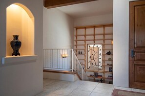 A staircase with a wooden railing, a vase on a shelf, and a door with a wooden frame.