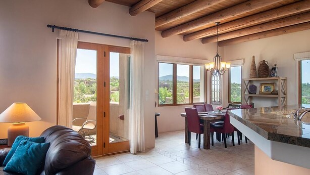Amplia habitación con comedor, sofá, candelabro y vistas al exterior.