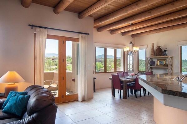 A spacious room with a dining area, a sofa, a chandelier, and a view of the outdoors.