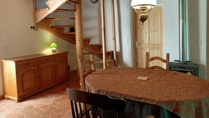 Ein rustikaler Raum mit einer Holztreppe, einem Esstisch mit Stühlen, einem Schrank und einer Wandleuchte.