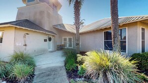 A two-story house with a covered porch, a private shower, and a small garden with various plants. - Lighthouse Unit B - 2 bedrooms, 2 bathrooms (Jekyll Island)