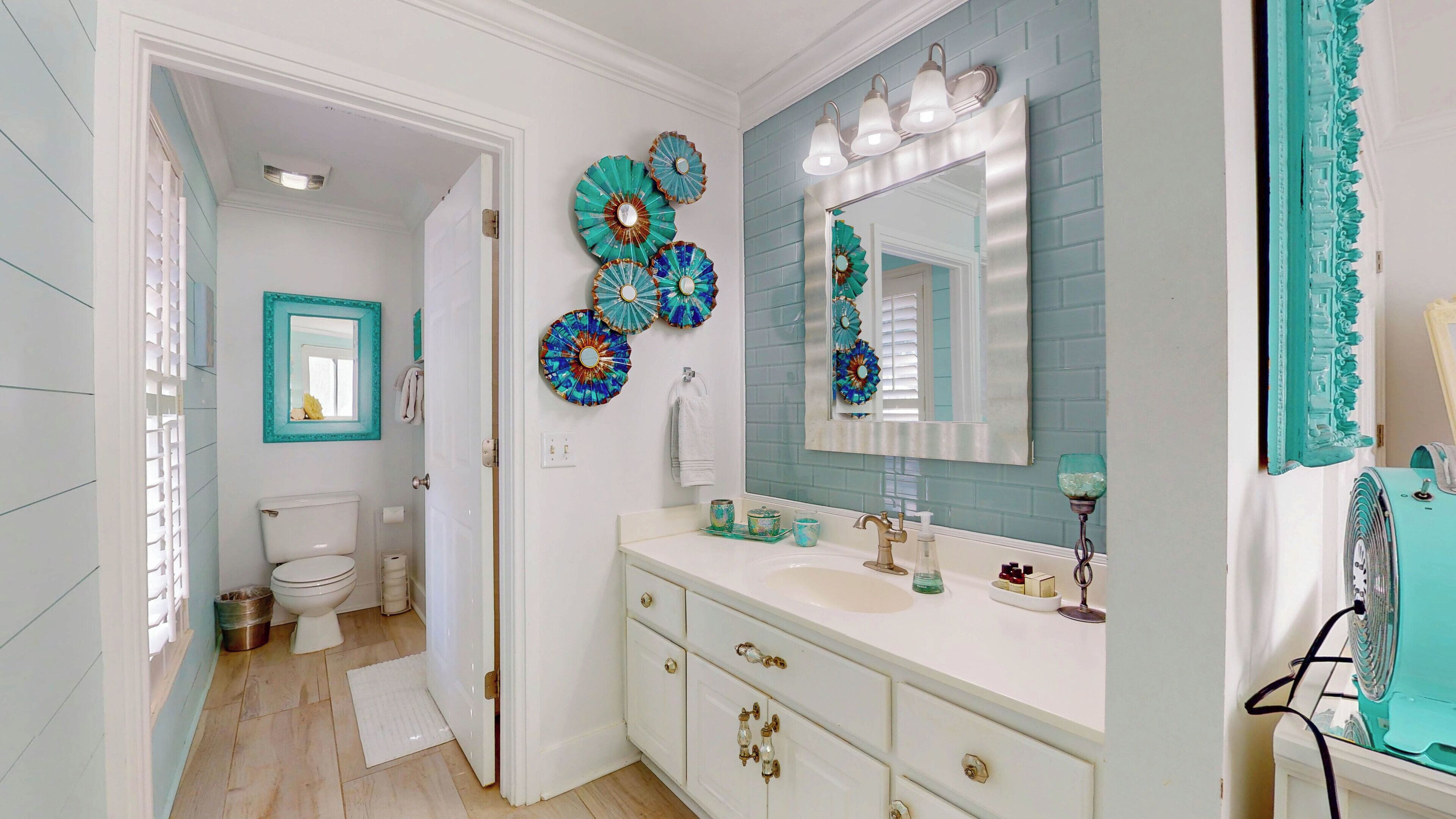 A bathroom with a white sink, a mirror, and decorative plates on the wall.