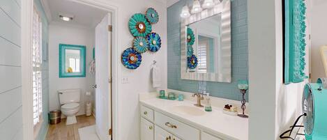 A bathroom with a white sink, a mirror, and decorative plates on the wall.