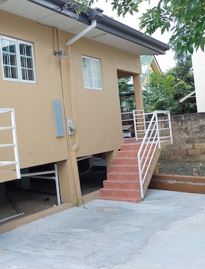 A residential building with a beige exterior, a staircase leading to a covered entrance, and a visible doorbell. - Santa Fe (Port of Spain)