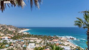 A coastal view with a beach, palm trees, and buildings. - Costa Azul Condo - Beach front and Ocean Views (San Jose Del Cabo)
