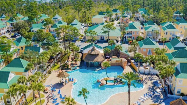 A resort with multiple buildings, a central swimming pool, and surrounding palm trees. - Coastal Tranquility: Beautiful Condo Offering Poolside Serenity Near Beach (Pensacola)