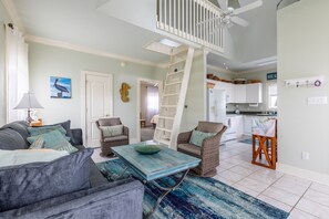 A spacious living room with a high ceiling, a dining area, and a kitchen.