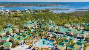 An aerial view of a resort with multiple buildings, a central pool, and surrounding greenery. - Coastal Tranquility: Beautiful Condo Offering Poolside Serenity Near Beach (Pensacola)