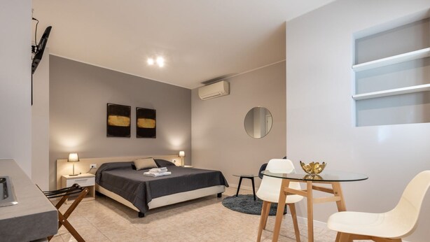 A modern bedroom with a bed, bedside tables, a desk, and chairs. - Residence Bonomelli apt. no. 15 studio apartment (Bergamo)
