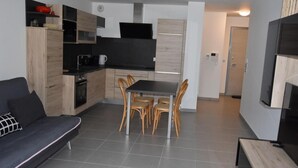 Una cocina moderna con comedor, un sofá y un televisor en la pared.