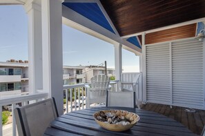 Een balkon met een tafel en stoelen, een kom met schelpen en een uitzicht op gebouwen op de achtergrond.